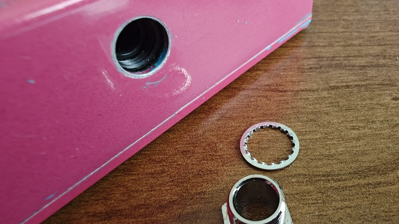 Photo of an MXR Fat Sugar with the jack ferrule removed.  MXR uses lock washers under the ferrule instead of an insulating washer.  The lock washer scrapes through the powder coat making a connection from the case aluminum to the metal ferrule.